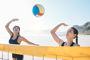 Image showing Woman, volleyball and teamwork in sports game, match or competition together by net in the outdoors. Female person, friends or team playing volley reaching for ball in fitness or athletics in nature