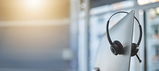 Image showing Call center, headset on a computer in an empty office with flare and mockup for communication or assistance. Customer care, support and equipment in a workplace after hours for help or service