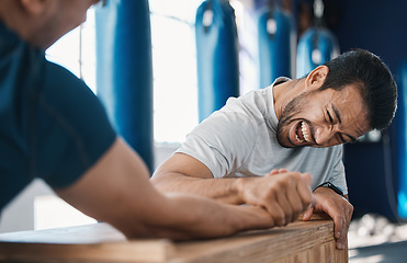 Image showing Strength, motivation and men arm wrestling in a gym on a table while being playful for challenge. Rivalry, game and male people or athletes doing strong muscle battle for fun, bonding and friendship.