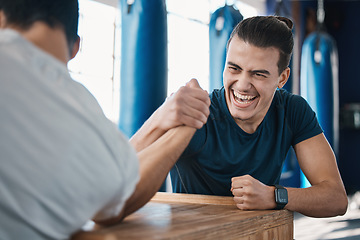 Image showing Strong, active and men arm wrestling in the gym on a table while being playful for a challenge. Rivalry, game and male people or athletes doing strength muscle battle for fun, bonding and friendship.