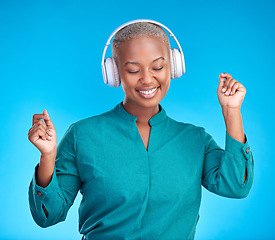 Image showing Black woman, headphones and studio with dancing, smile and listen to music by blue background. Young gen z student, sound tech and happy for audio streaming subscription, radio or excited with dance