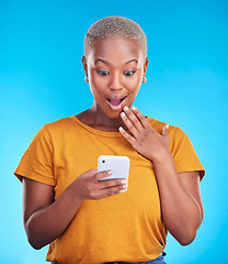 Image showing Studio, phone and black woman surprise over reading announcement, winner notification or online sales news. Discount promotion, smartphone information and shocked African person on blue background