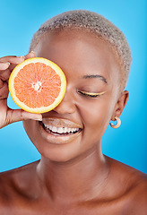 Image showing Orange fruits, skincare and face of black woman in studio, blue background and eco makeup cosmetics. Beauty, happy female model and citrus for vitamin c, facial detox or healthy aesthetic dermatology