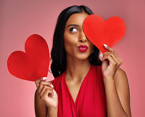 Image showing Red heart, woman in studio and kiss emoji on background for romance, emotion and fun symbol. Happy indian female model, thinking and pout with paper shape for love, icon or flirting on valentines day