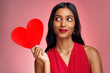 Image showing Woman, paper heart and thinking in studio with makeup, beauty and romantic sign by red background. Young girl, ideas and cardboard emoji with love for cosmetics, valentines day date and aesthetic