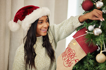 Image showing Christmas, decoration or excited girl with tree in home for fun holiday or vacation break with smile. Relax, happy or Indian woman hanging ornaments or decorations for festive celebration in house