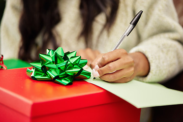 Image showing Woman, hands and writing on Christmas gift, note or letter in surprise, festive season or December holiday. Hand of female person with pen and paper on present or box with ribbon for package in house