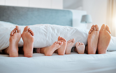 Image showing Bed, feet and family together in the morning, sleeping or rest in bedroom on holiday, weekend or vacation. Mom, dad and children resting, dreaming or calm relaxing in home, house or hotel with kids