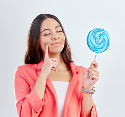 Image showing Woman, face and thinking of lollipop, candy or sweets for junk food, snack or unhealthy decision. Curious, doubt or studio person wonder about sugar calories, choice or dessert on white background