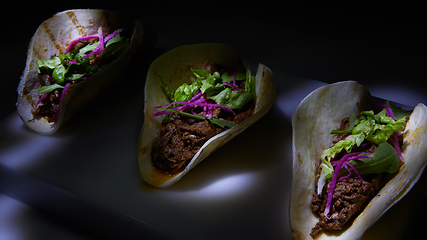 Image showing Three pork carnitas street tacos in yellow corn tortilla.