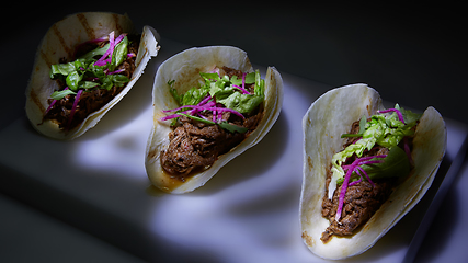 Image showing Three pork carnitas street tacos in yellow corn tortilla.