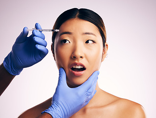 Image showing Woman, needle and fear on face in studio for surgery, cosmetics and shock with collagen by white background. Japanese patient, doctor and syringe for dermatology, change and pain for skin aesthetic