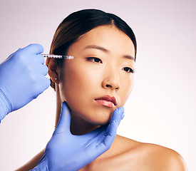 Image showing Asian woman, beauty and needle for surgery in studio for cosmetics, eye filler or collagen by white background. Hands, doctor and syringe for patient, transformation or change with collagen in face