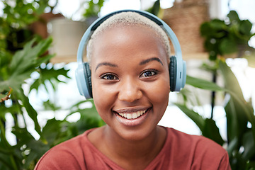 Image showing Portrait, music and headphones with a black woman in her home by plants while streaming an audio playlist. Face, radio and subscription service with a carefree young female person in her house