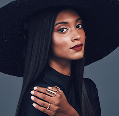 Image showing Fashion, face and confident woman with hat in studio isolated on a gray background. Portrait, style and serious female model from India with makeup cosmetics, classy clothes and elegant aesthetic.