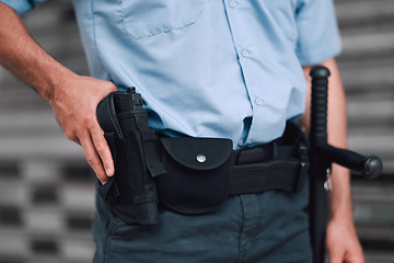 Image showing Hand, gun and security with an officer on duty or patrol in the city for safety and law enforcement. Police, service and armed response with a guard outdoor in an urban town for crime prevention