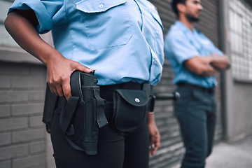Image showing Hand, gun and security with a police officer on duty or patrol in the city for safety and law enforcement. Legal, service and armed response with a guard outdoor in an urban town for crime prevention