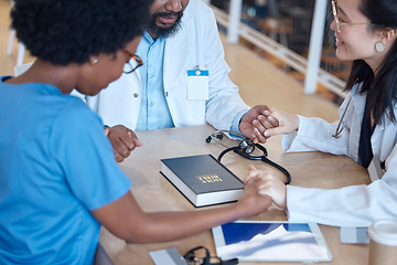 Image showing Hands, bible and a medical team praying during a meeting in a hospital office together. Medical, trust or teamwork with doctors and nurses asking God or Jesus for miracle help in a health clinic