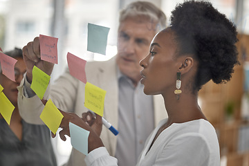 Image showing Meeting, planning and glass with a black woman leading a presentation in a boardroom for company strategy. Teamwork, presentation and sticky notes in an office with a female employee talking to staff