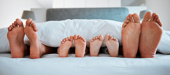 Image showing Family feet, bed and blanket in closeup, parents or kids sleeping on holiday in morning, care and relax. Bedroom, people and sleep with mom, dad or children on vacation, home or break in hospitality