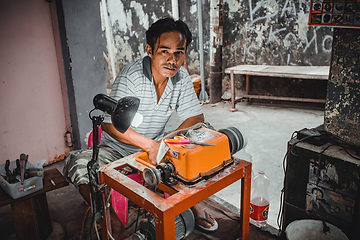 Image showing Man with grinder machine working on the street, Indonesia