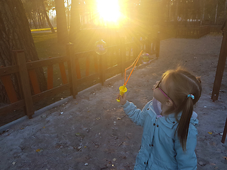 Image showing A little girl blowing soap bubbles in summer park. Background toninf for instagram filter