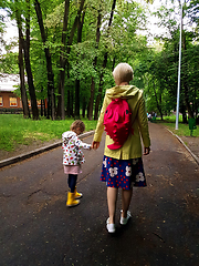 Image showing Mother and little curly toddler girl walking together in a park 