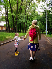 Image showing Mother and little curly toddler girl walking together in a park 