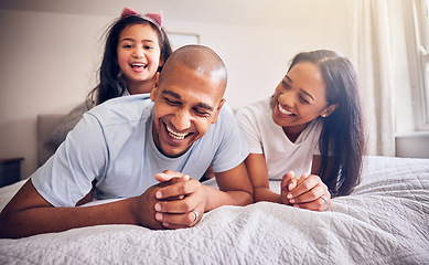 Image showing Family, relax and happy on a bed at home while laughing and playing for funny quality time. Man, woman or parents and a girl kid together in the bedroom for morning bonding with love and care