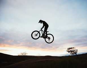 Image showing Jump, motorcycle and sunset with sport or sky and adventure in nature with risk or speed. Freedom, action and hill with silhouette with dirt bike in outdoor with training or race or power, danger.