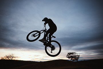Image showing Motorcycle, sunset and jump with sport with sky or action with training in outdoor for race or risk. Adventure, silhouette and dirt bike with speed in nature with freedom or power in desert on hill.