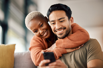 Image showing Phone, interracial couple and technology on a sofa at home reading text in a living room. Support, young people and hug together in a house sitting on a lounge couch with mobile streaming and video