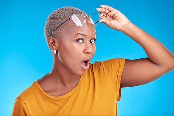 Image showing Portrait, news and black woman shocked, gossip and announcement against a blue studio background. Face, female person and model with glasses, surprise and deal with omg facial and wow with expression