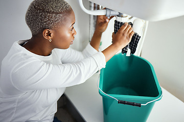 Image showing Plumbing, water and a black woman in the bathroom of her home with a cloth and bucket waiting for assistance. Sink, emergency and burst pipe with a young female homeowner in her house to stop a leak