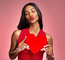 Image showing Woman, paper heart and kiss in studio with lips, makeup and beauty with romantic sign by red background. Girl, fashion model and cardboard emoji with love for cosmetic, valentines day date or pout