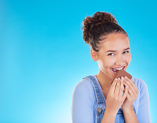 Image showing Chocolate, diet and space with portrait of woman in studio for fast food, dessert and nutrition. Happy, cacao and sugar with person eating on blue background for candy, health and hungry mockup