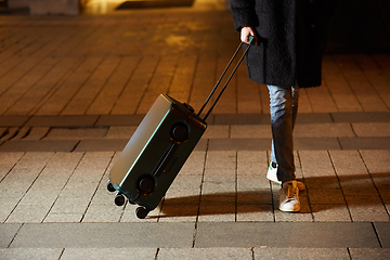 Image showing Young woman walking around the city. Her hand is holding luggage.