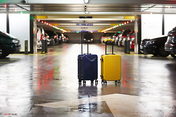 Image showing Orange suitcase on the road in city. Summer vacation and travel concept