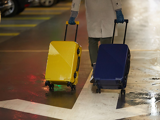 Image showing Back view of walking woman with two suitcase. Beautiful girl in motion. Backside view of traveler with baggage