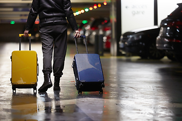 Image showing Back view of walking woman with two suitcase. Beautiful girl in motion. Backside view of traveler with baggage