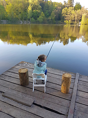 Image showing lonely little child fishing from wooden dock on lake