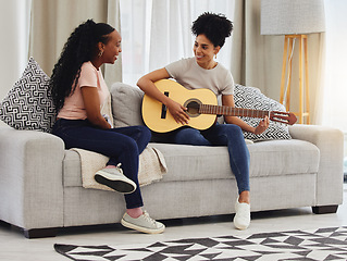 Image showing Guitar, happy or women in house for music, social or entertainment while laughing together on sofa. Smile, acoustic or creative musician friends with an instrument for artistic expression in a home