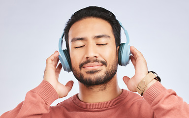 Image showing Man, headphones and calm music in studio, white background and podcast for peace. Face of happy young asian male model listening to audio, streaming sound and hearing radio to relax with song in mind