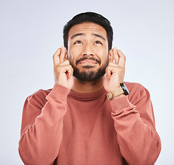 Image showing Fingers crossed, hope and man with hands for good luck, anxiety or trust for bonus on white background in studio. Nervous asian male person wish for belief, emoji and prayer for winning lottery prize