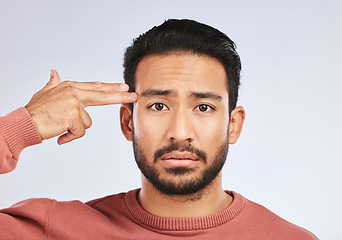 Image showing Depression, portrait and sad asian man with hand gun in studio for suicide, trauma or ptsd fail on grey background. Stress, face and guy with weapon emoji for death, anxiety or mental health crisis