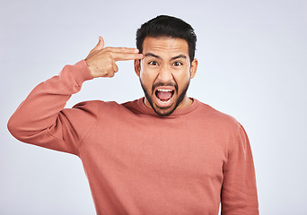 Image showing Portrait, angry and asian man with hand gun in studio for suicide, threat or shooting warning on grey background. Screaming, stress and face of male person with anxiety, self harm or bipolar crisis