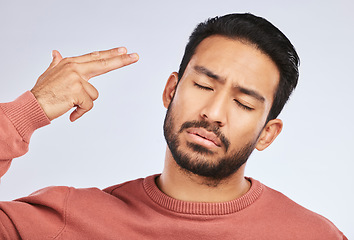 Image showing Depression, face and asian man with hand gun in studio for anxiety, trauma or ptsd on grey background. Finger, suicide and male sad with stress, anxiety or self harm, bipolar or mental health crisis