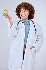 Image showing Doctor, woman and smile with apple in studio, white background and wellness. Happy medical employee, female nutritionist and holding green fruits for vitamin c nutrition, healthy food and vegan diet