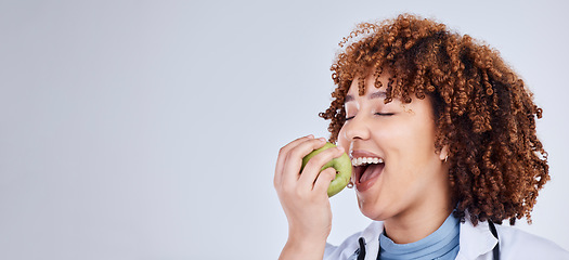 Image showing Doctor, woman and eating apple in studio, white background and mockup space. Face of medical employee, happy female nutritionist and bite fruits for vitamin c nutrition, healthy food and vegan diet