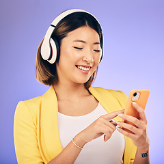 Image showing Headphones, music and happy Asian woman with phone in studio for social media, subscription and radio. Female person on smartphone listening to audio, song and track on purple background to relax